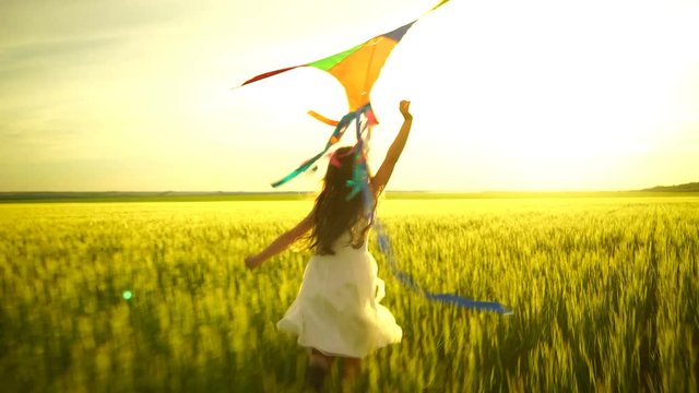 girl running around with a kite on the field.