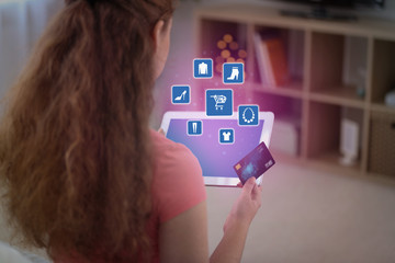 Young woman with credit card using tablet for online shopping at home