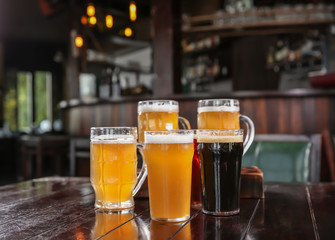Glasses of tasty beer on wooden table in bar