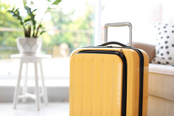 Bright yellow suitcase packed for journey at home