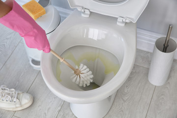 Fototapeta na wymiar Woman cleaning toilet bowl in bathroom, closeup