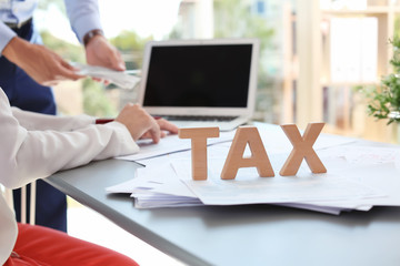 Word TAX and blurred accountants on background