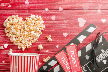 Flat lay composition with tasty popcorn, tickets and clapboard on red wooden background. Cinema...