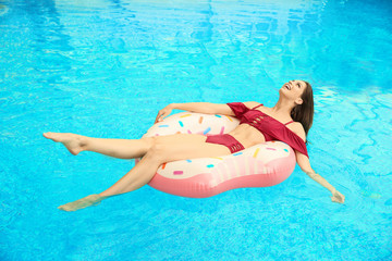 Beautiful young woman on inflatable ring in swimming pool