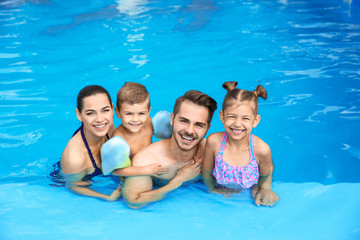 Young family with little children in swimming pool on sunny day