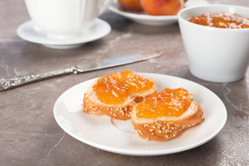 Plate with bread and tasty peach jam on table