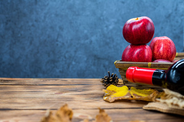 Fall harvest cornucopia. Basket with red apple and wine on the table. Copy space on wood background...