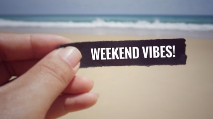 Motivational and inspirational quote - ‘Weekend vibes!’ written on piece of paper. Blurred...