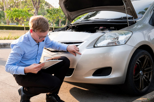 Insurance agent writing document on clipboard examining car after accident, Insurance concept