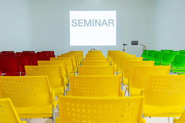 Ready to use rows of colorful chairs in conference room with words seminar on wall as projector screen