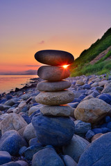 pyramid of pebbles against the backdrop of the sunset and the sea