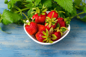 Ripe strawberries and fresh mint on blue wooden background