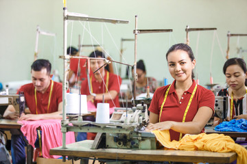 asian workers in garment factory sewing with industrial sewing m