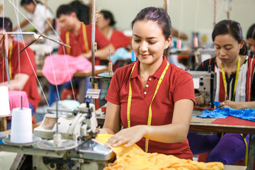 Seamstress in textile factory sewing with industrial sewing mach
