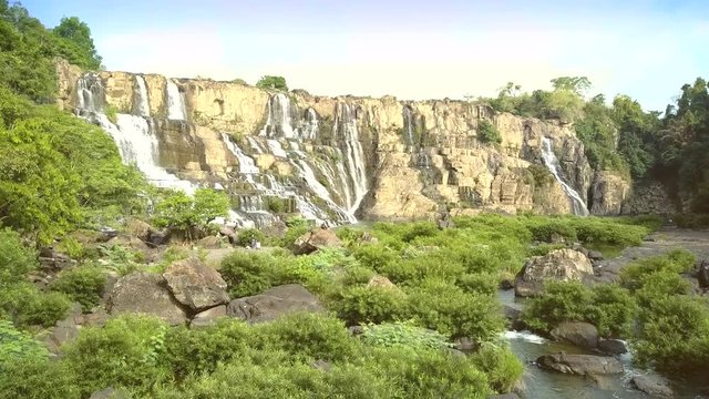 camera moves close to waterfall tourists walk around