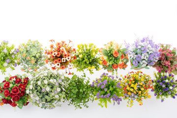 Rows of colorful fake flowers on white background, made from cloth and plastic for decoration