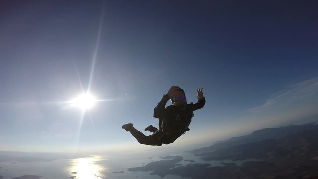 Skydiver having fun above the sea & mountains 4K
