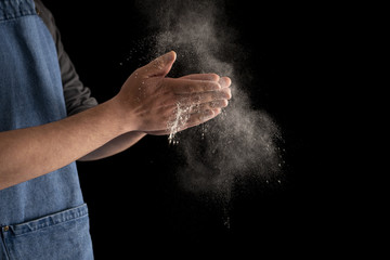 Fototapeta na wymiar Baker Dusting Hands with Flour on Black Background