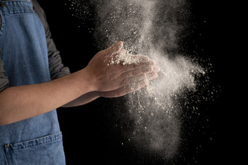 Fototapeta na wymiar Dusting Hands with Flour on Black Background