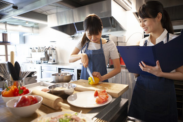 野菜の選び方、調理法などを学び、メモを取る女性と講師