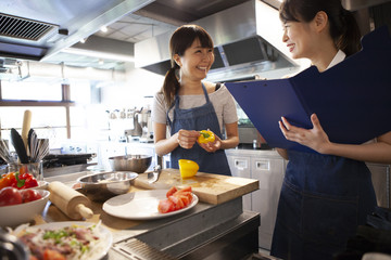 野菜の選び方、調理法などを学び、メモを取る女性と講師