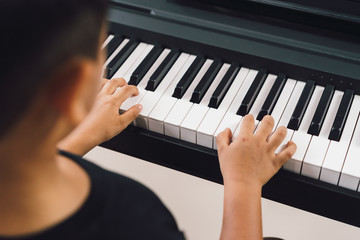 An asian boys  playing the piano.