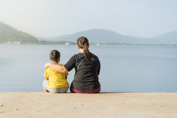 Mothers and children sit  at the Bang Phra reservoir in the sunset
