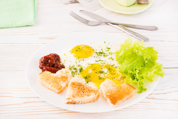 Scrambled eggs, fried bread, ketchup and lettuce leaves on a plate on the table. Ready-to-eat breakfast