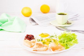 Scrambled eggs, fried bread, ketchup and lettuce leaves on a plate, cup of coffee and newspaper on the table. Ready-to-eat breakfast
