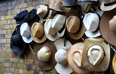 Viele, wundervolle Hüte an einer Backsteinwand hängend