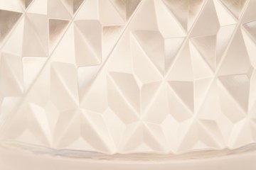 Macro abstract background of beautiful lead crystal glass with diamond cut surface patterns reflecting white color giving an artistic painted appearance