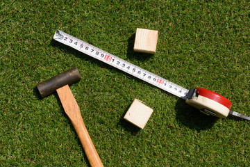 tools(hammer, wood, measure) on green grass