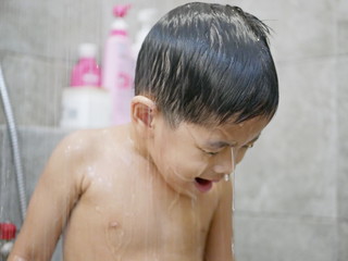 Fototapeta na wymiar Asian baby girl's head / hairs, 30 months old, in a water from a rain shower - baby learning to breathe through her mouth to take a shower like an adult