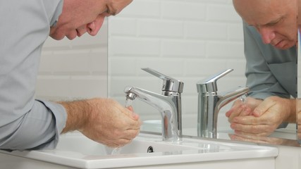 Tired Man in Bathroom Washing His Face with Fresh Water from Sink Faucet