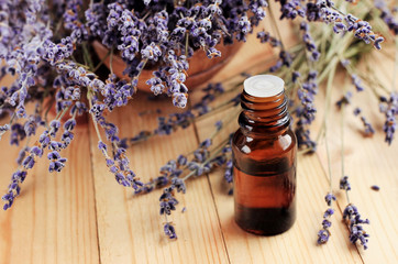 Healing lavender essential oil for beauty treatment and home deodorant. Dried purple plant flowers, dark glass dropper bottle, wooden table. Natural aromatherapy.