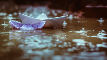Fototapeta na wymiar Close up a paper boat floating or sailing in water