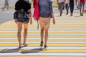 Legs of a girl crossing the road through a zebra