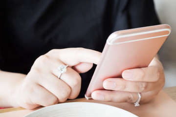 Woman with diamond ring on hand using smartphone in cafe restaurant