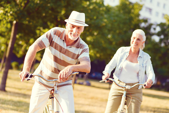 What A Lovely Day. Relaxed Elderly Man Looking Into The Camera With A Cheerful Smile On His Face After Spending His Day Outdoors And Bicycling With His Wife.