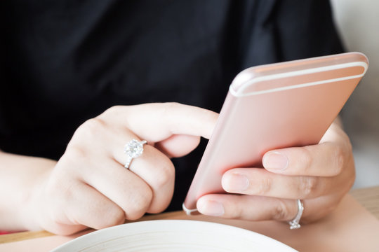 Woman With Diamond Ring On Hand Using Smartphone In Cafe Restaurant