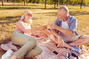 Cheers. Extremely happy husband and wife smiling to each other while sitting outdoors and enjoying...