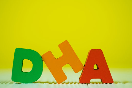 DHA text alphabet on white wooden table. yellow wall background with copy space.