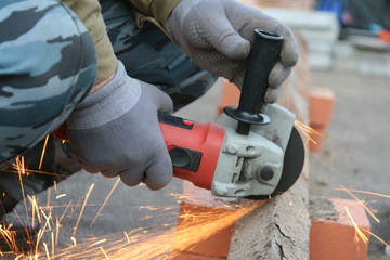 Close-up of worker cutting metal with grinder. Sparks while grinding iron. Low depth of focus