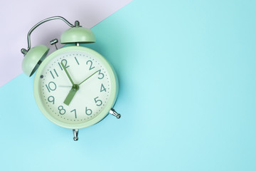 Vintage alarm clock on sweet pastel colored paper top view, background texture, pink, purple, yellow, beige, green and blue colour.
