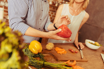 Listen to me. Delighted woman standing near her boyfriend and listening him attentively while cooking salad together