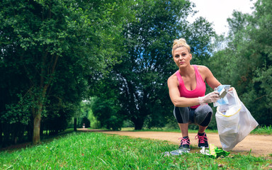 Girl crouching with bag picking up trash doing plogging