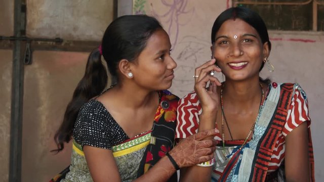 Static of happy friends at home with a smart phone mobile talking looking at camera they share happy news laugh smile joy happiness fun togetherness bonding sharing caring ethic wear traditional dress