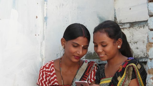 Tilt down to women dress colorful buddies laugh and share photo video secrets love on the phone laugh thumbs up congratulate well done wow fantastic awesome joy ecstatic closeup pan left