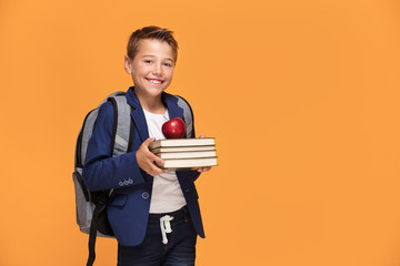 Little school boy with backpack and books.