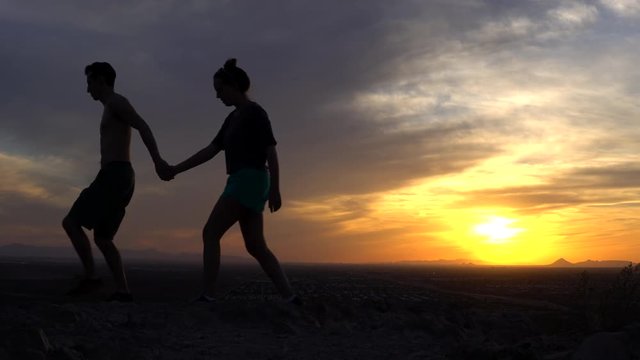 man leading woman across sunset left